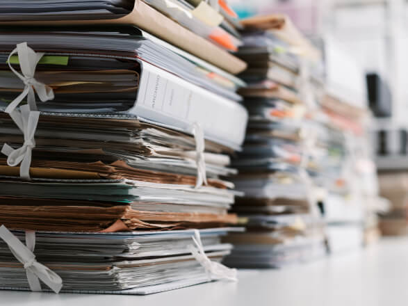 Pilhas de papéis e documentos Papéis e documentos empilhados em uma mesa de escritório. Resultado de uma gestão de documentos ineficiente.