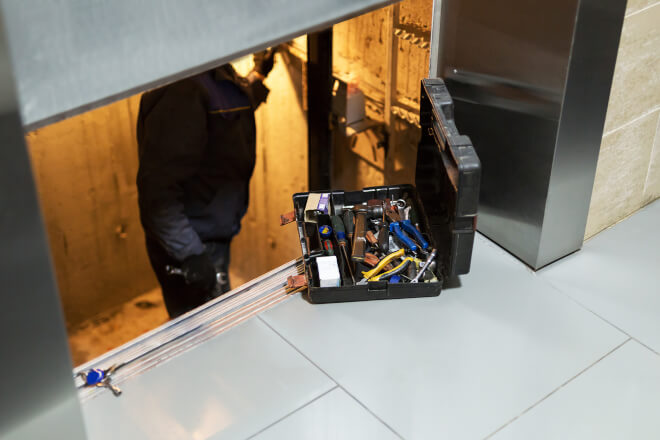 Técnico fazendo manutenção e ajustes em um elevador