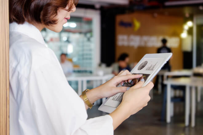 Gestora de operações analisa dados e rotinas por meio de um software em uma plataforma móvel.